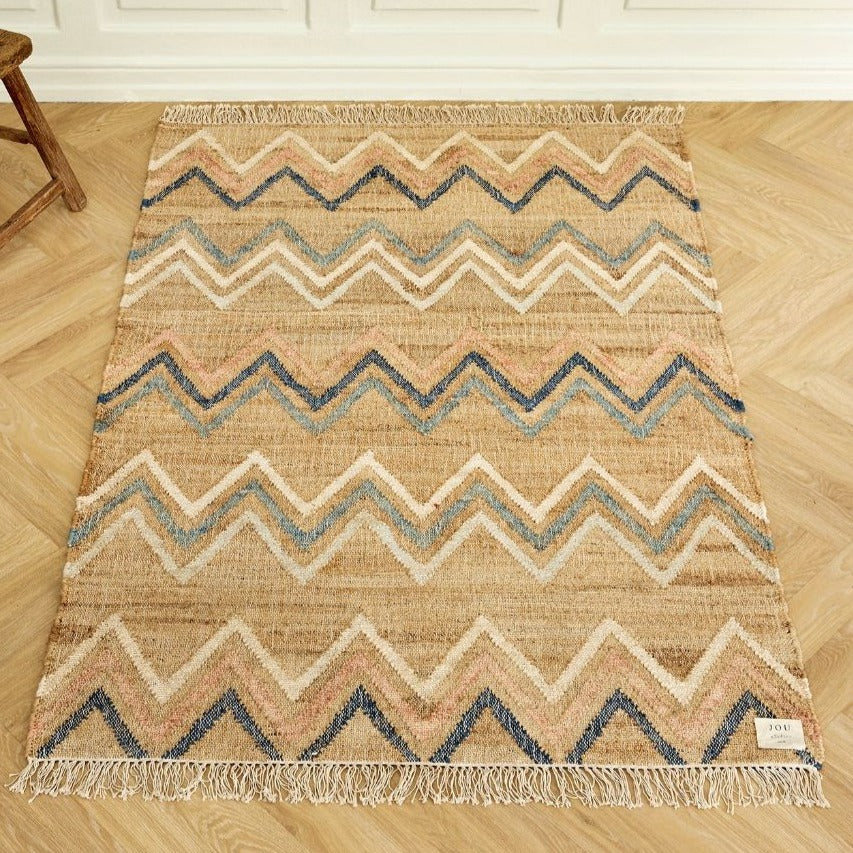 Tæppet er bl.a. lavet i jute, som er et fantastisk naturfiberprodukt og som med det samme giver et rum en dejlig varm atmosfære. Farven er beige/brun med mønster i farverne blå, hvid og lyserød.