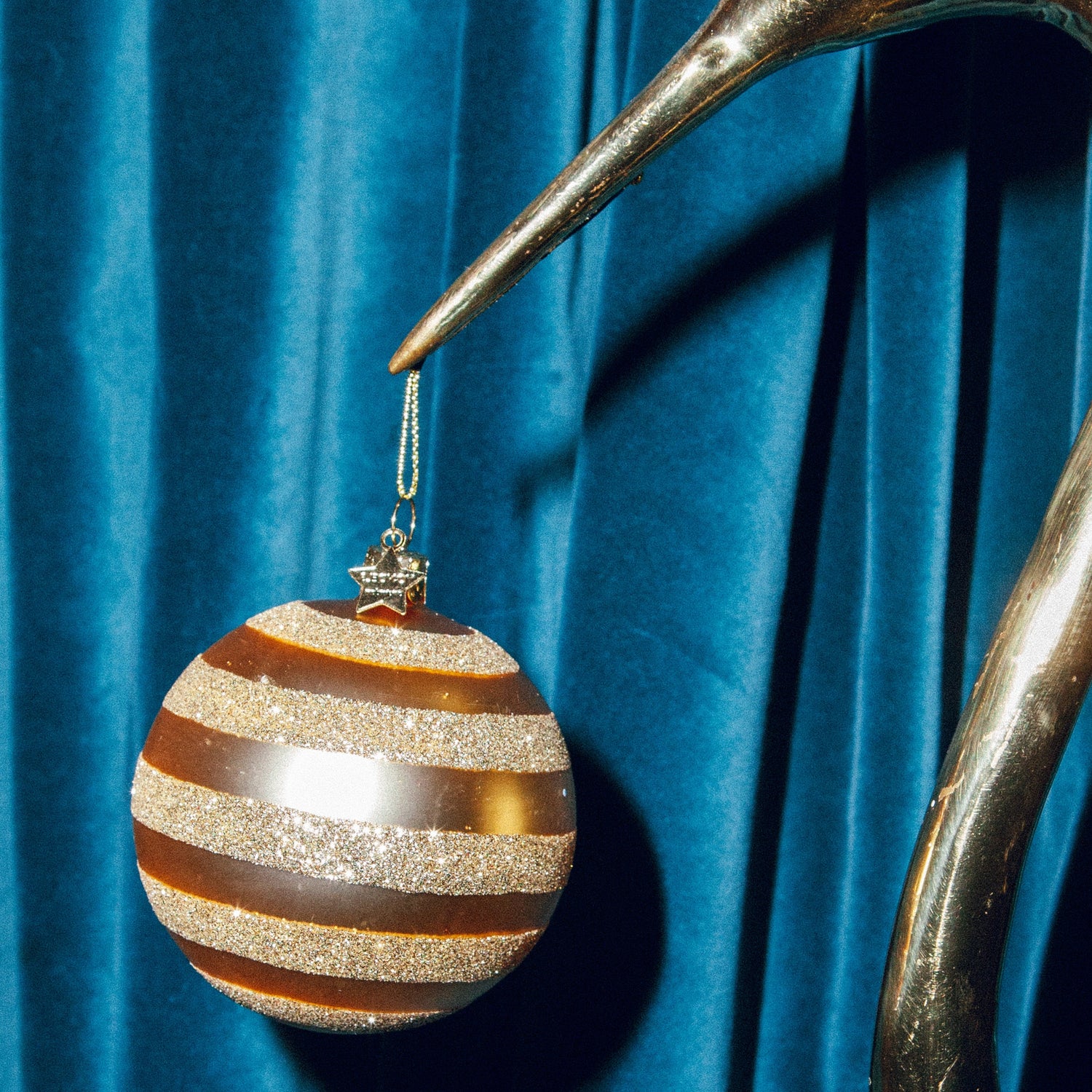 Rund klassisk julekugle i guld med gule striber, der følger kuglen rundt