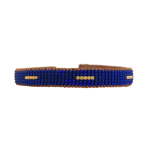 Winter Stripe armbåndet fra IBU Jewels er et fint perlearmbånd med en farve som base, hvor der er en samling af 5 små guldperler i midten af armbåndet samt samlinger af perler på tværs af armbåndet. Armbåndet er lavet af eksklusive Miyuki-perler, som er håndsyet på blødt læder. Denne model er med blå perler som base.