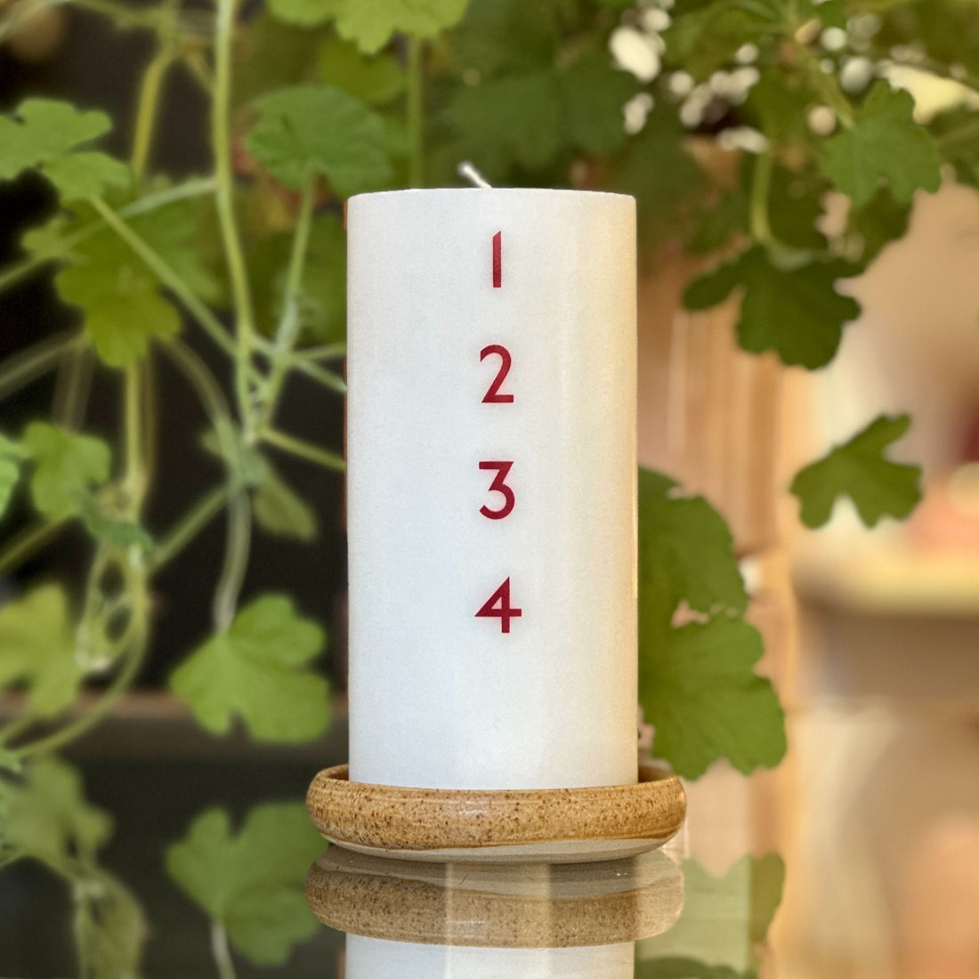 Bredt adventslys med røde tal. Adventsyset består af 51% sojavoks og 49% stearin, og er derfor det tætteste, man kan komme på et soja-kalenderlys.