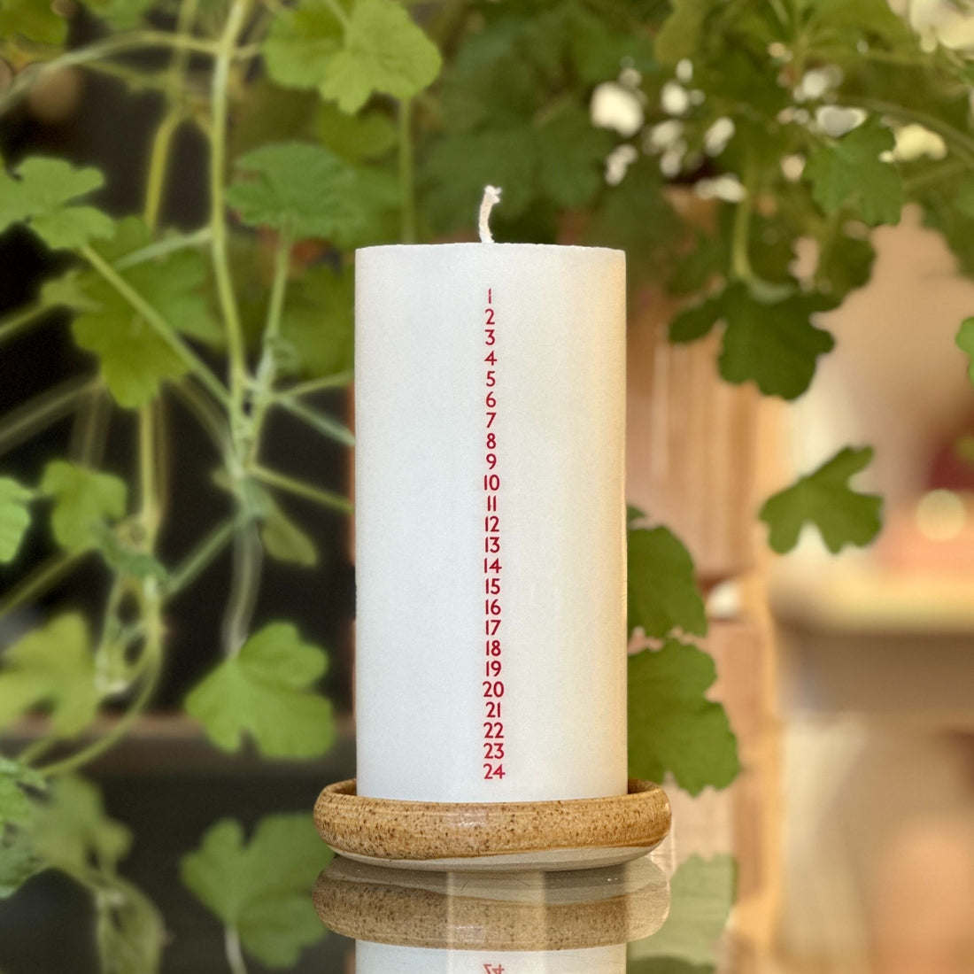 Hvidt kalenderlys med røde tal. Kalenderlyset består af 51% sojavoks og 49% stearin, og er derfor det tætteste, man kan komme på et soja-kalenderlys.