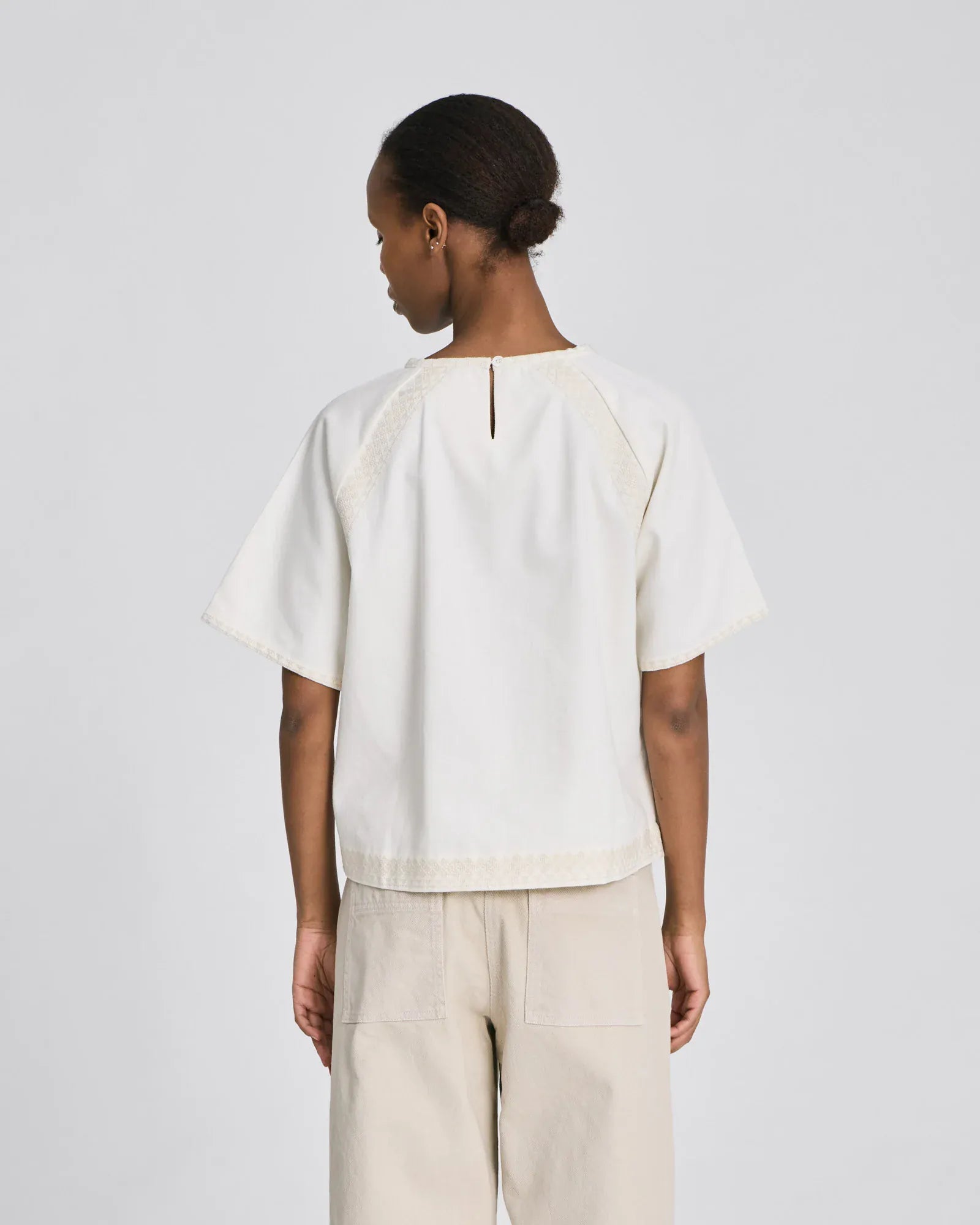 Bagside af Angie T-shirt med broderi og nøglehulslukning i økologisk bomuld.