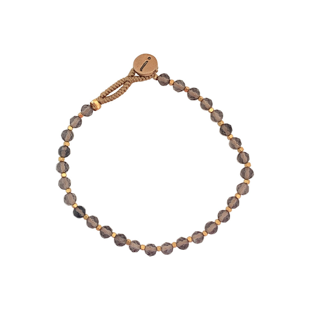 'Bo Round' armbåndet fra IBU Jewels er et enkelt armbånd, som primært består af perler med en enkelt guldperle imellem. 'Smokey' består af en base af grå sten. Hvis du tager armbåndet op i lyset vil perlerne vise sig fra forskellige vinkler.