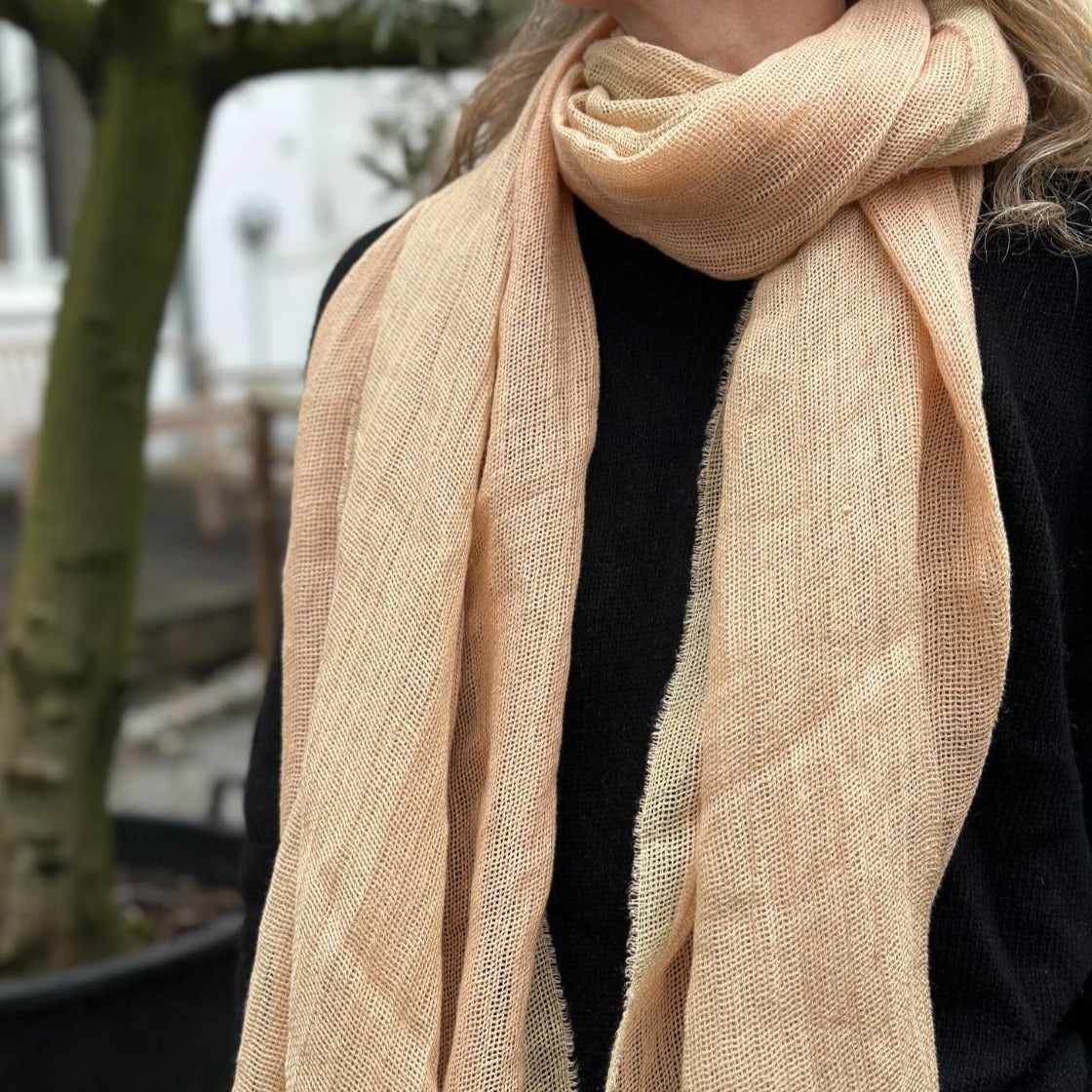 Et beige tørklæde. Tørklædet er lavet i hør