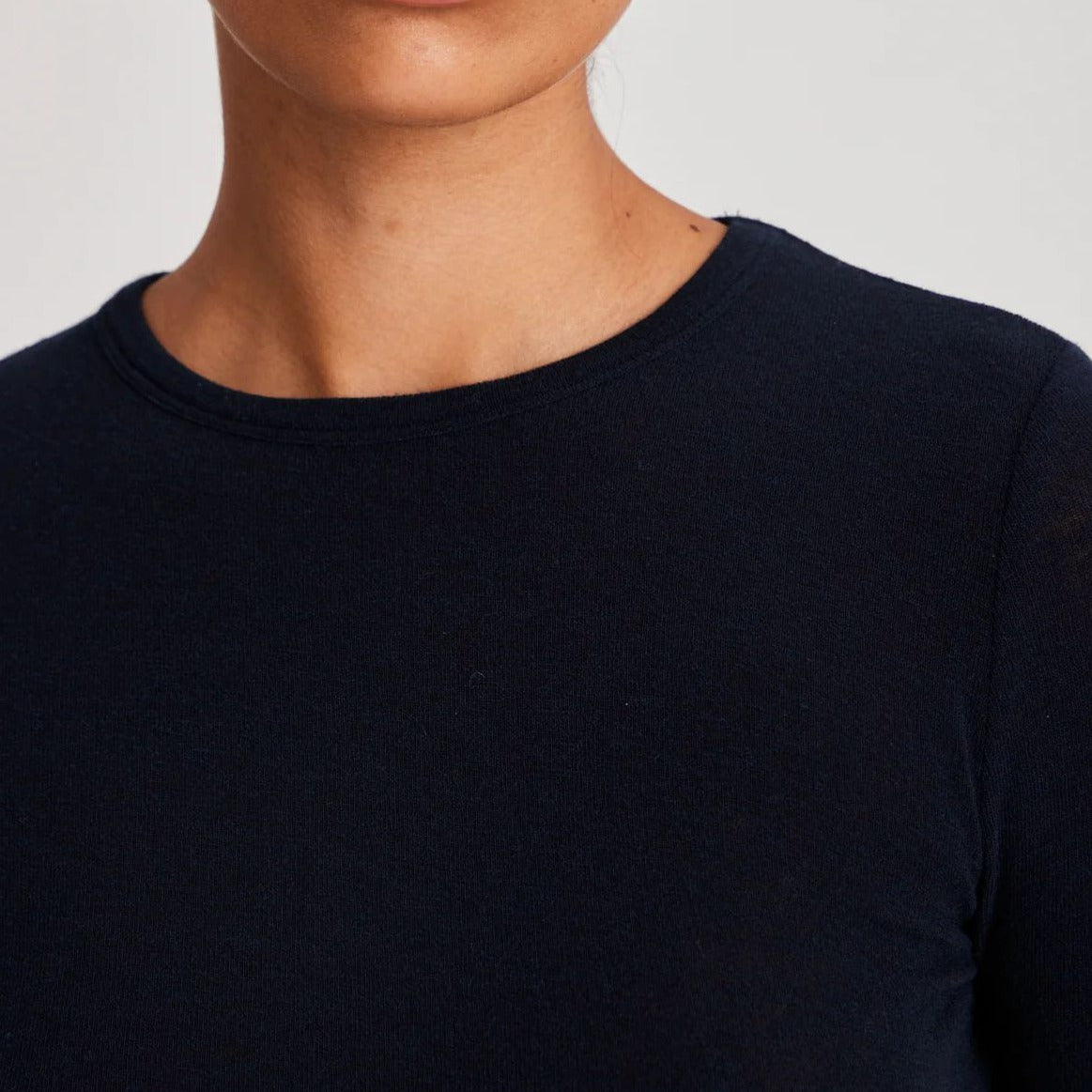 Thyra er en langærmet basisbluse i uld, som holder dig varm. Den er høj i halsen og er mørkeblå
