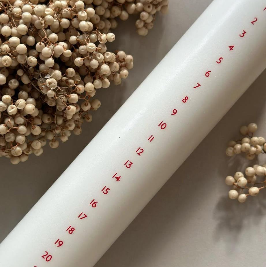 Højt hvidt kalenderlys med røde tal. Kalenderlyset består af 51% sojavoks og 49% stearin, og er derfor det tætteste, man kan komme på et soja-kalenderlys.