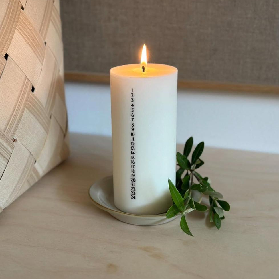 Hvidt kalenderlys med sorte tal. Kalenderlyset består af 51% sojavoks og 49% stearin, og er derfor det tætteste, man kan komme på et soja-kalenderlys.