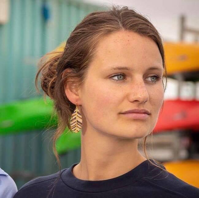 Smukke øreringe formet som blade. De er lavet af små fine perler i guld, rosa, blå og brun. Her ses det på et øre