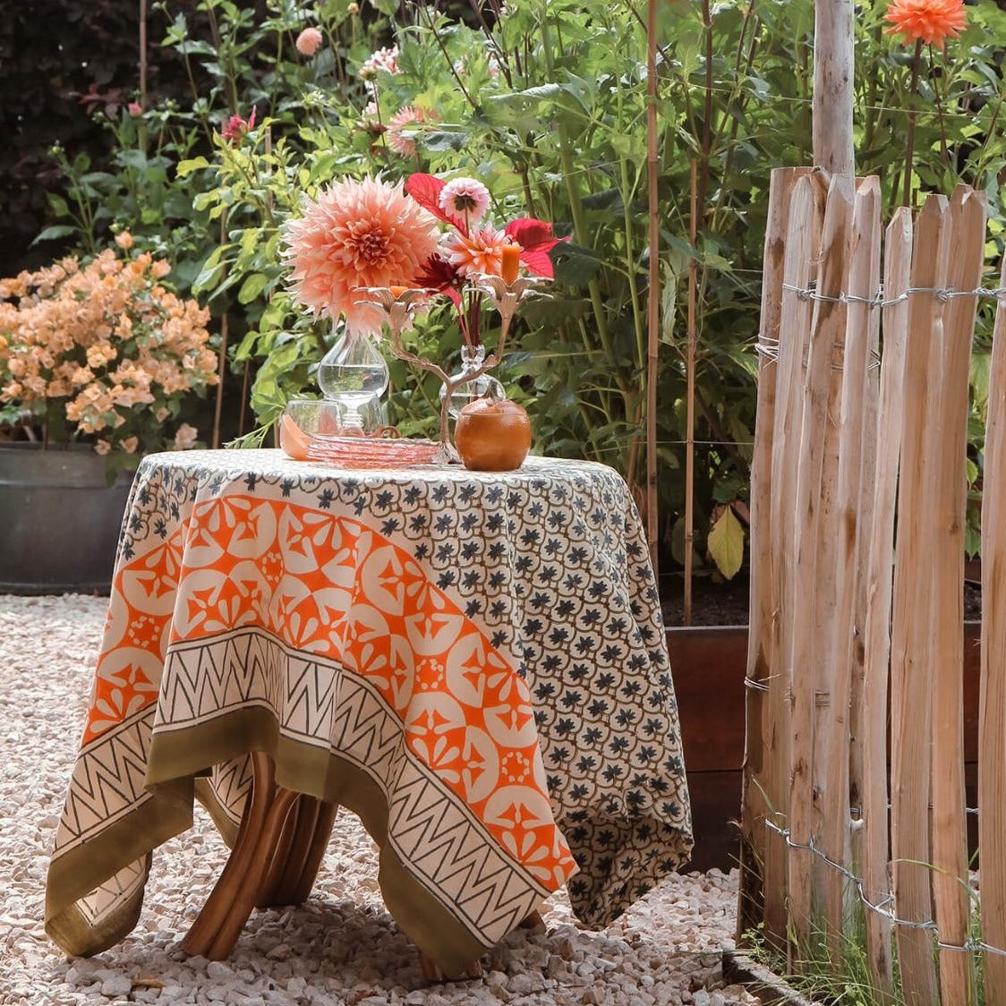 Et dug/sengetæppe med et grønt blomstermønster i midten og en orange og grøn kant