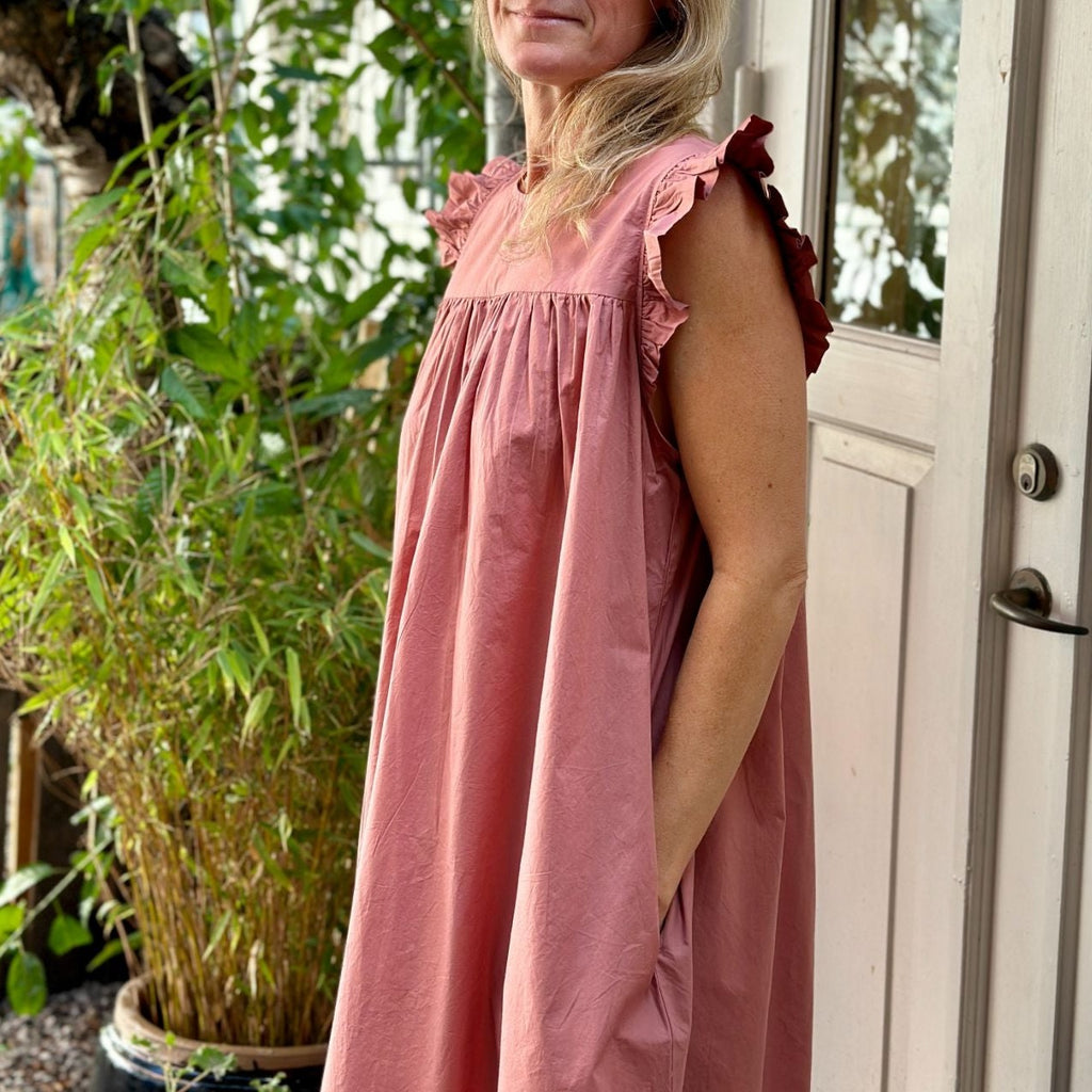 Stockholm kjolen fra FRAU er en lang kjole med flæser ved ærmerne. Den er vendbar og er i farven 'ash rose', som er en støvet rosa