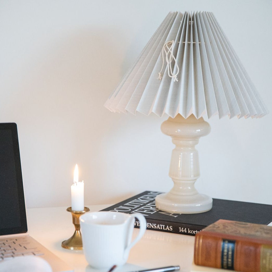 Denne mundblæste glaslampe er dansk design. Den er klassisk i sin udformning og er i farven beige opal, som er en mild beige farve. På billedet er den parret med en lys blå lampeskærm