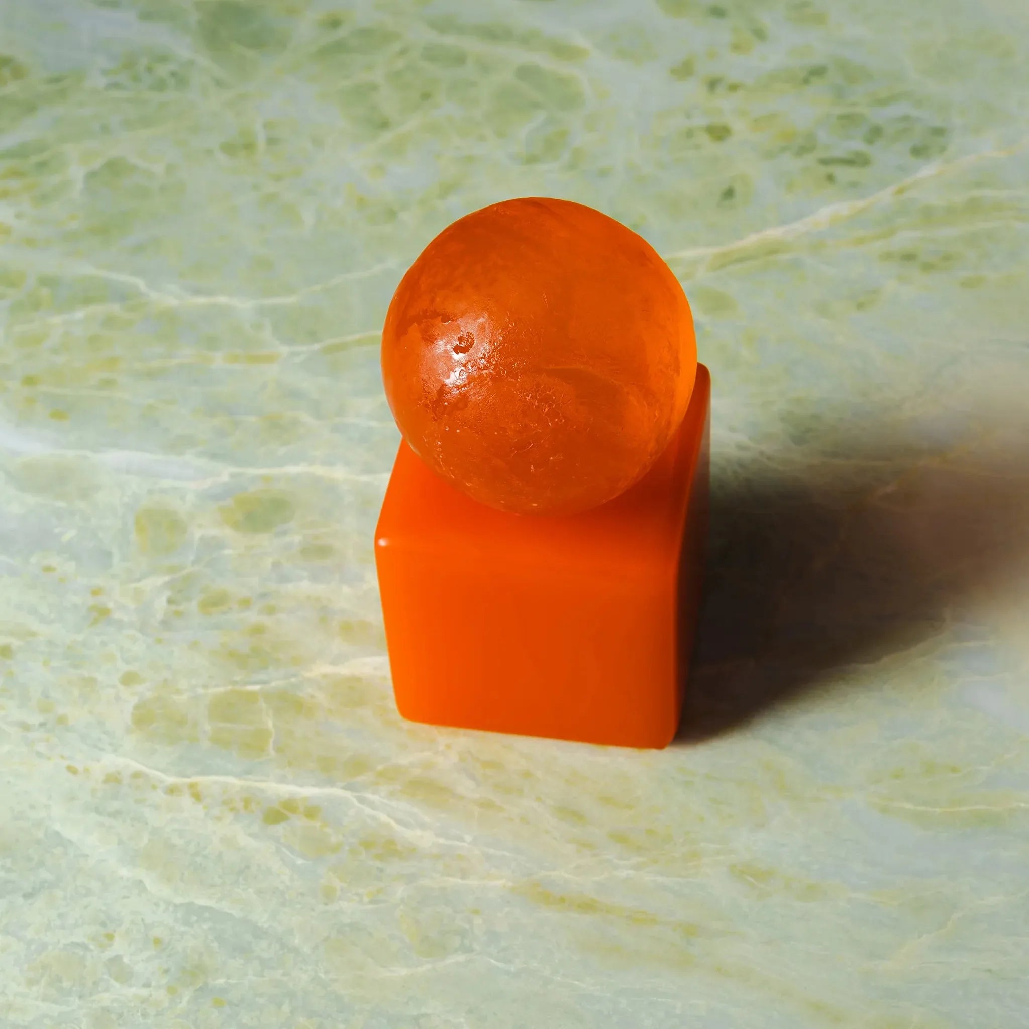 Dekorativ design sæbe med papayafarvet kugle og skulpturel holder