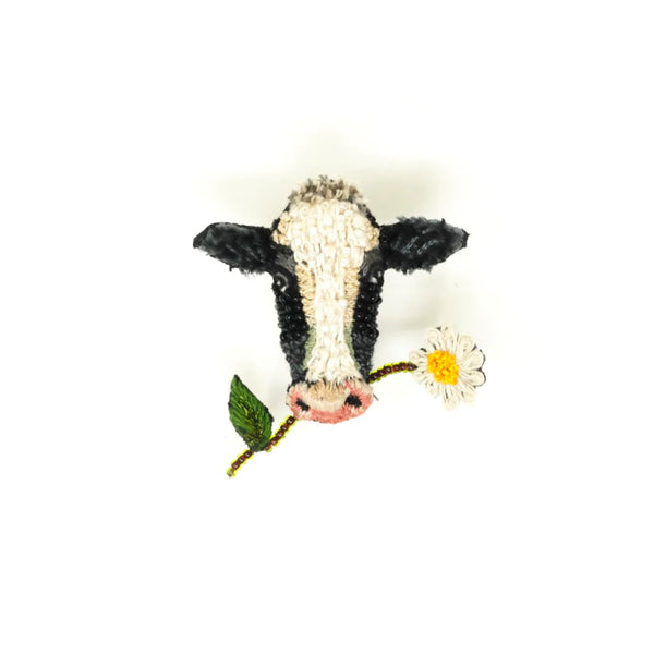 broche fra trovelore af en ko med en blomst i munden