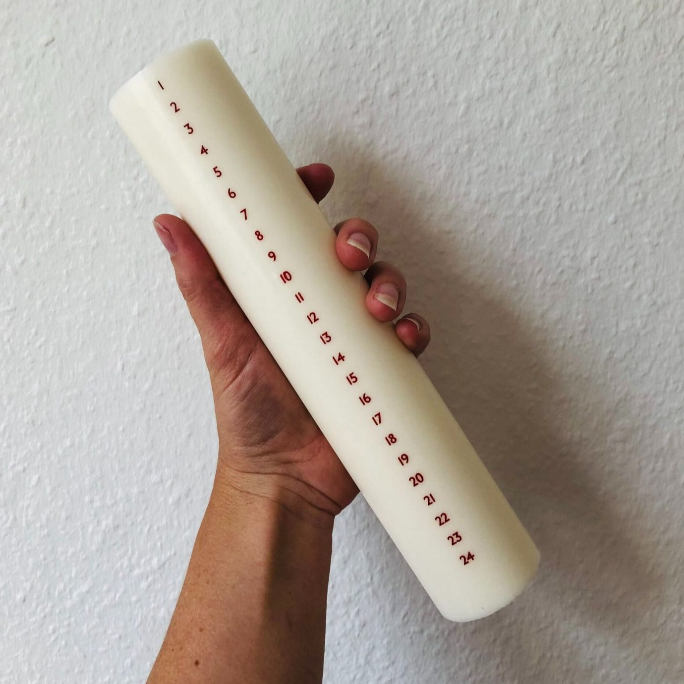 Højt hvidt kalenderlys med røde tal. Kalenderlyset består af 51% sojavoks og 49% stearin, og er derfor det tætteste, man kan komme på et soja-kalenderlys.