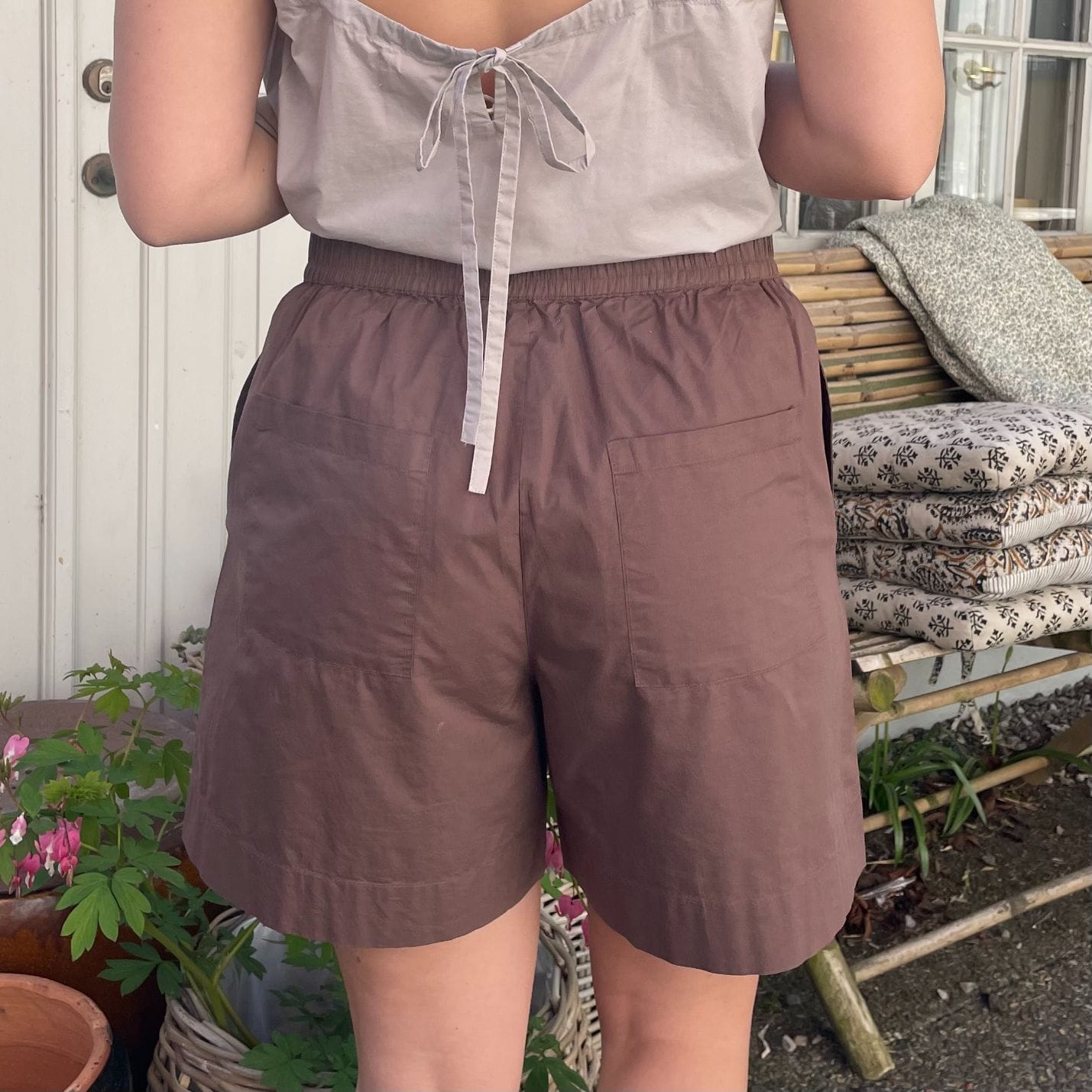 De nye Sydney Shorts i mørkebrun er endnu en tidløs klassiker til din garderobe fra danske Frau. Shortsene er lavet i et enkelt design med vide ben, baglommer, bred elastik i taljen og bindebånd.