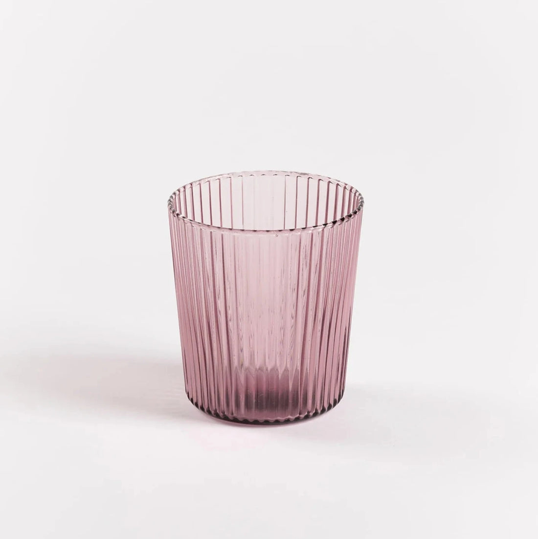 Farvet vandglas i en mørkere rosa farve. Glasset er riflet