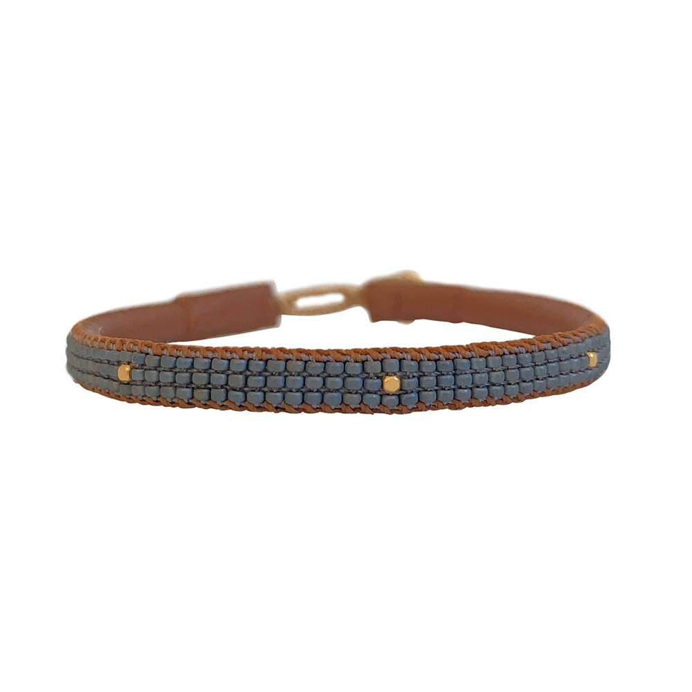 Otto armbåndet fra IBU Jewels er et fint perlearmbånd med en farve som base, hvor der er små guldperler på tværs af armbåndet. Armbåndet er lavet af eksklusive Miyuki-perler, som er håndsyet på blødt læder. Denne model er med grå perler som base.