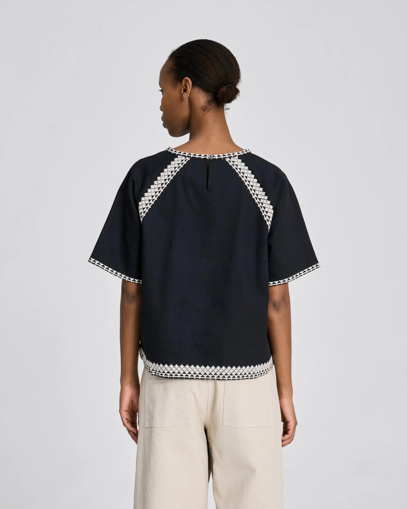 Sort Angie T-shirt i økologisk bomuld med hvide broderidetaljer og rund hals.