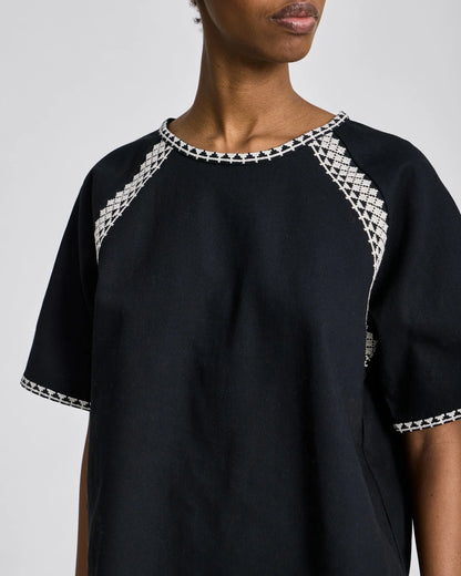 Detaljebillede af hvide broderi på sort Angie T-shirt i 100% økologisk bomuld.