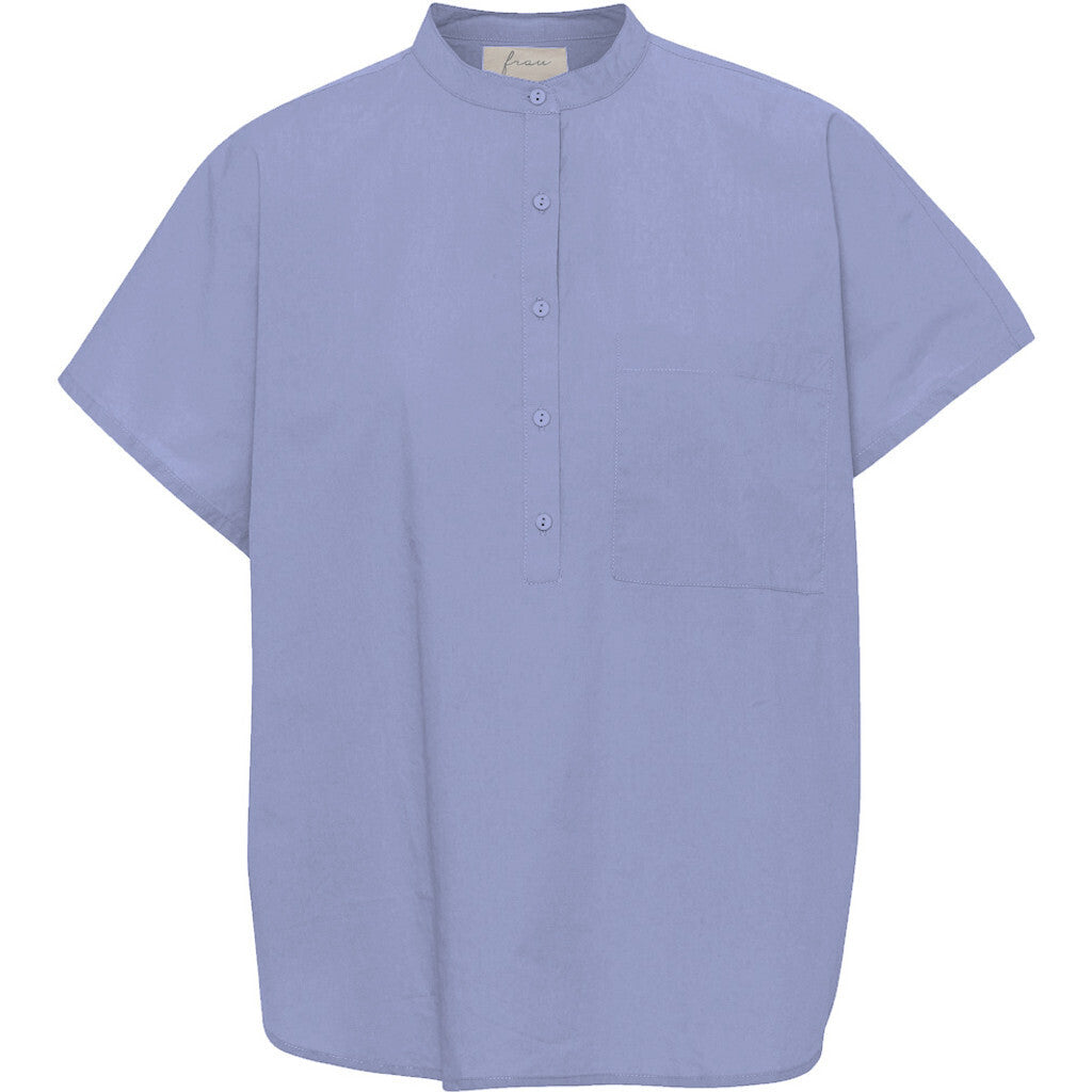 Den lyseblå kortærmede skjorte 'Columbo' fra Frau har et flot minimalistisk snit med kinakrave. T-shirten har stolpelukning, og er lavet i en let bomuldspoplin, som gør skjorten åndbar og super behagelig at have på. Modellen er one size og er lavet i 100% økologisk bomuld.