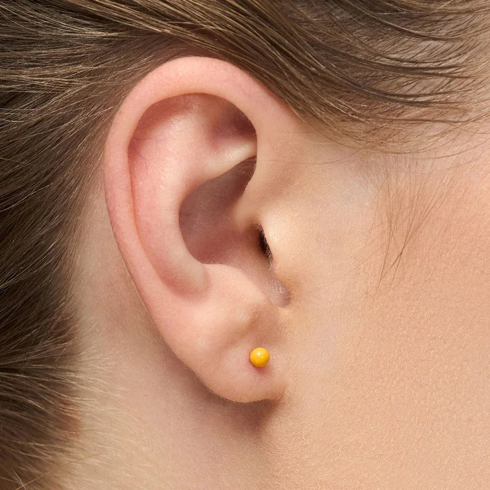 Ørering fra LULU Copenhagen med gul kugle og guldbelagt stift i enkelt design