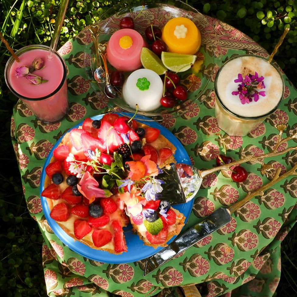 Et dug/sengetæppe med et grønt blomstermønster i midten og en lyserød og gul kant