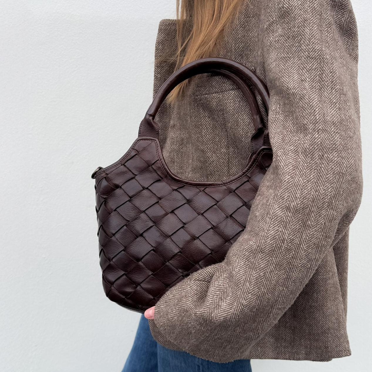 Mørkebrun flettet lædertaske fra Montana Est. 1957 med håndtag og aftagelig skulderrem.