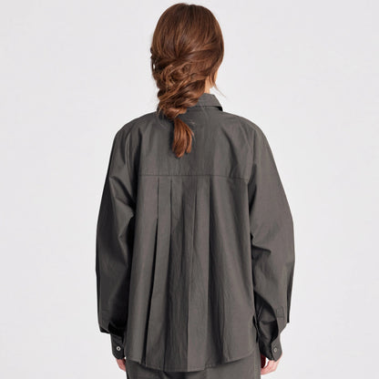 Bella er en lang skjorte med lange raglan ærmer, brystlomme samt knapper foran og på manchetter. Bella har plisseringer bagpå, slidser i siderne og er længere bagpå. Denne er i farven Beluga, som er en khaki/brun farve
