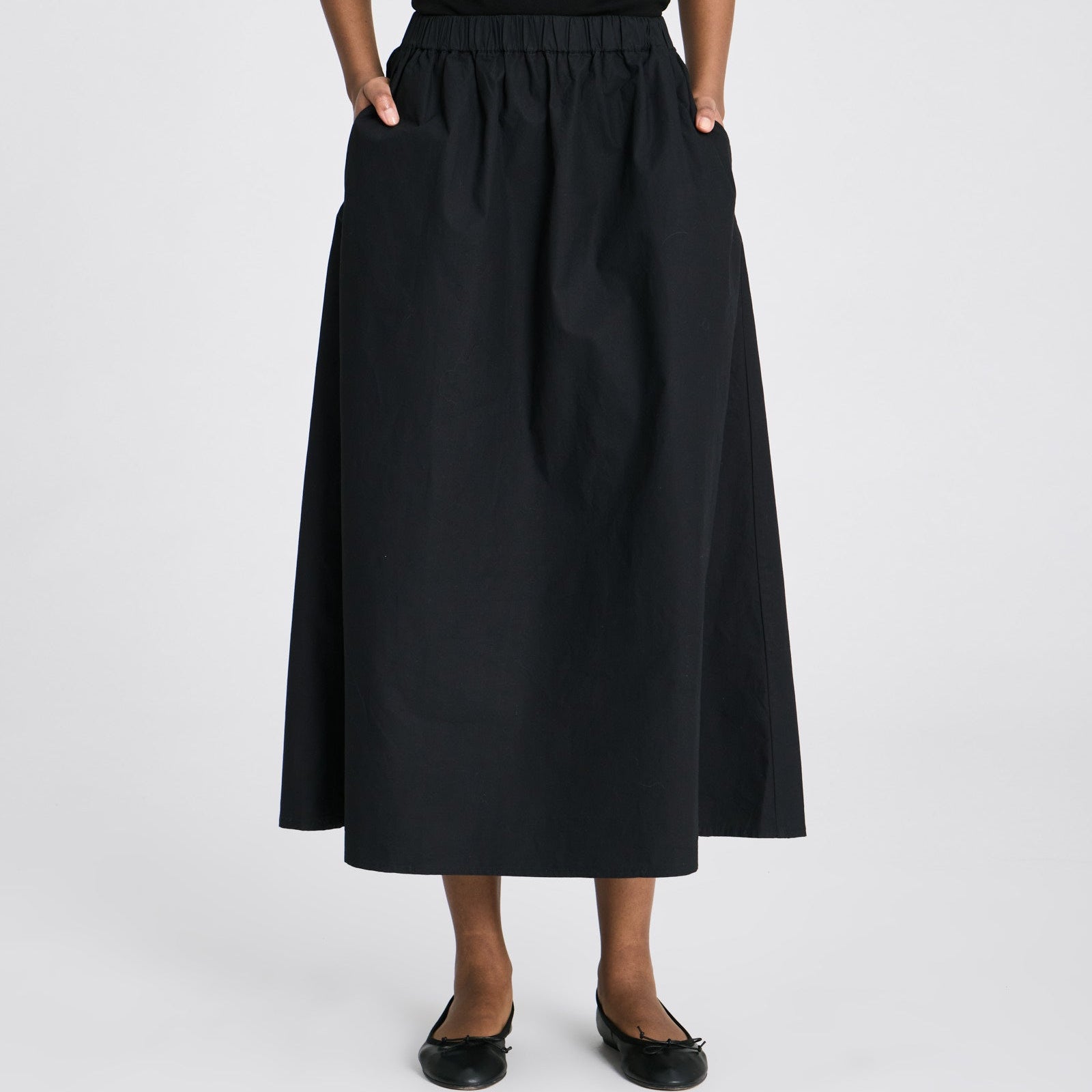 Sort Alice nederdel med let A-form, slidsdetaljer og praktiske stiklommer.