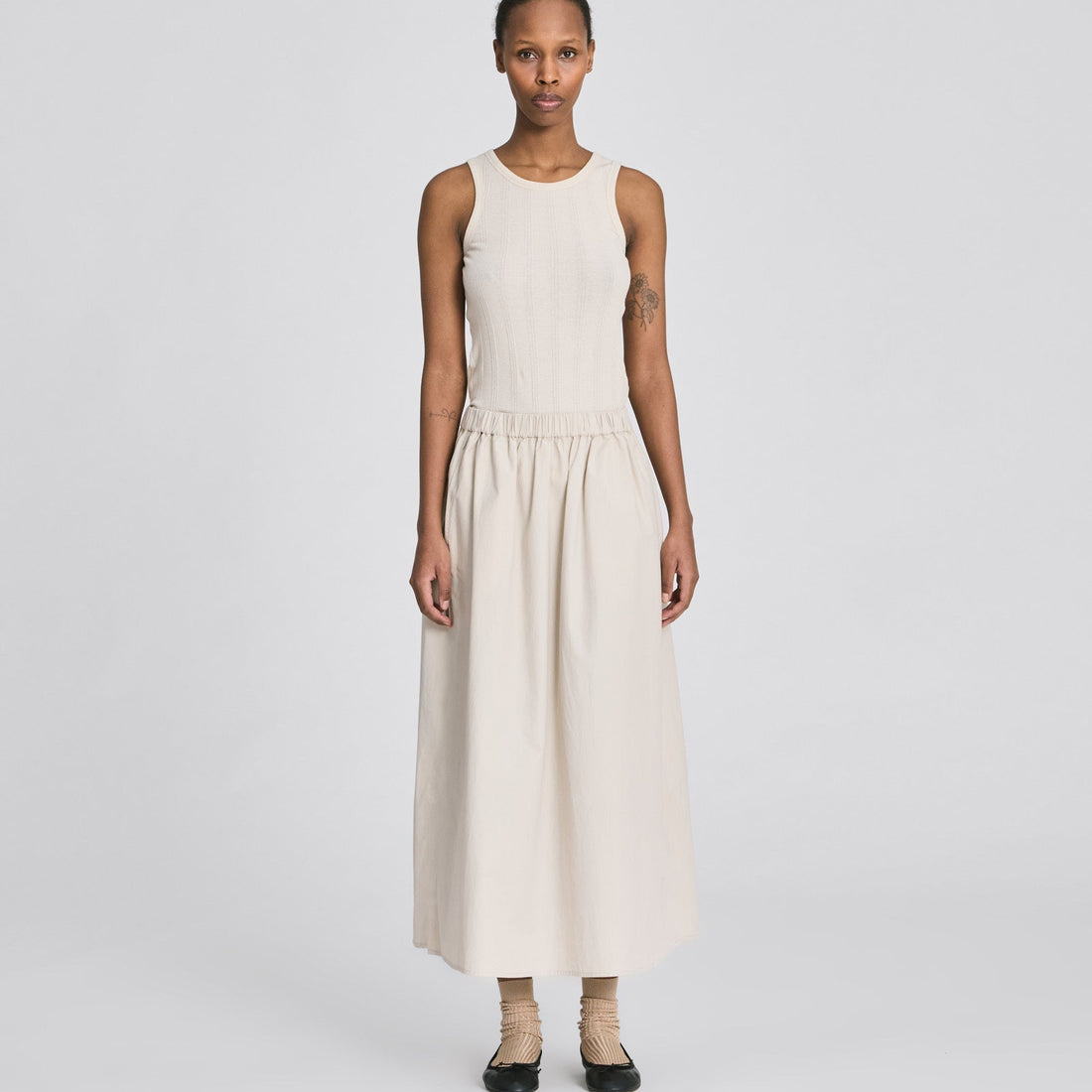 Cremehvid Alice nederdel med let A-form, slidsdetaljer og praktiske stiklommer.