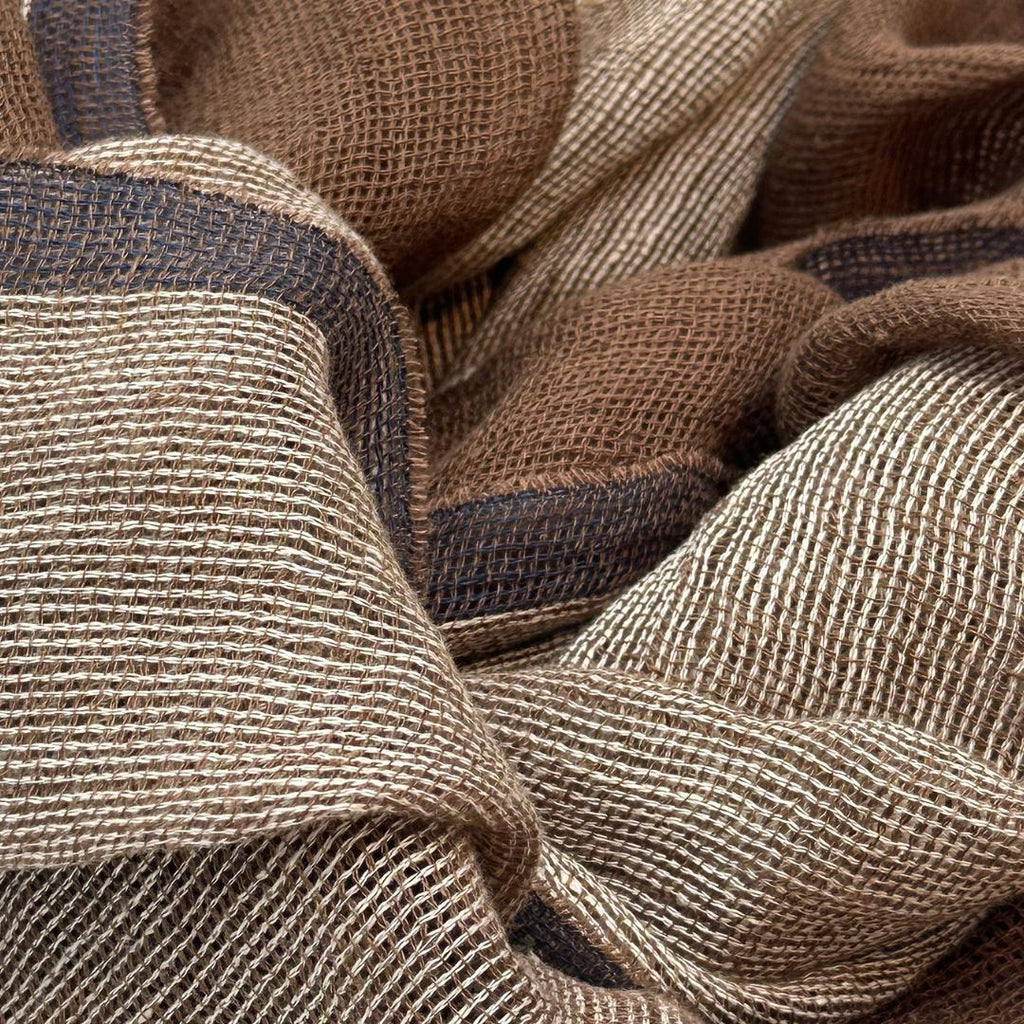 Et brunt tørklæde med en blå kant. Tørklædet er lavet i hør
