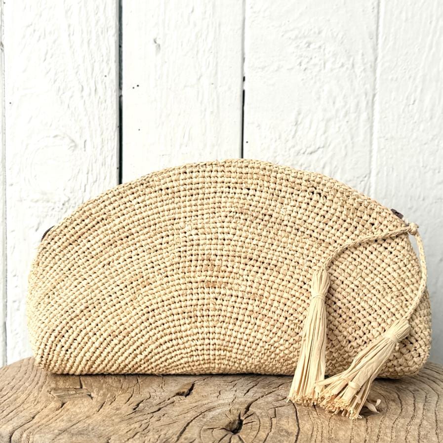 Lille clutch i raffia i klassisk naturfarve – et let og tidløst valg til både hverdag og sommerens events.