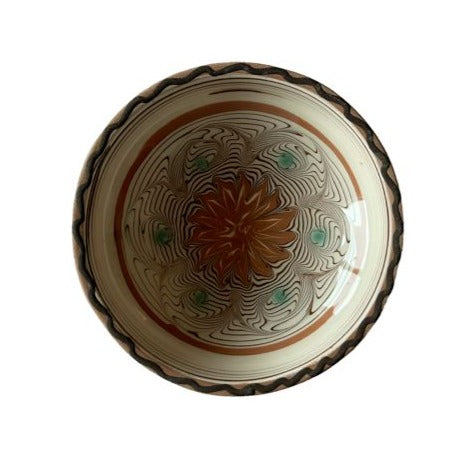En rumænsk keramikskål som er beige med bruge og grønne farver i sit mønster