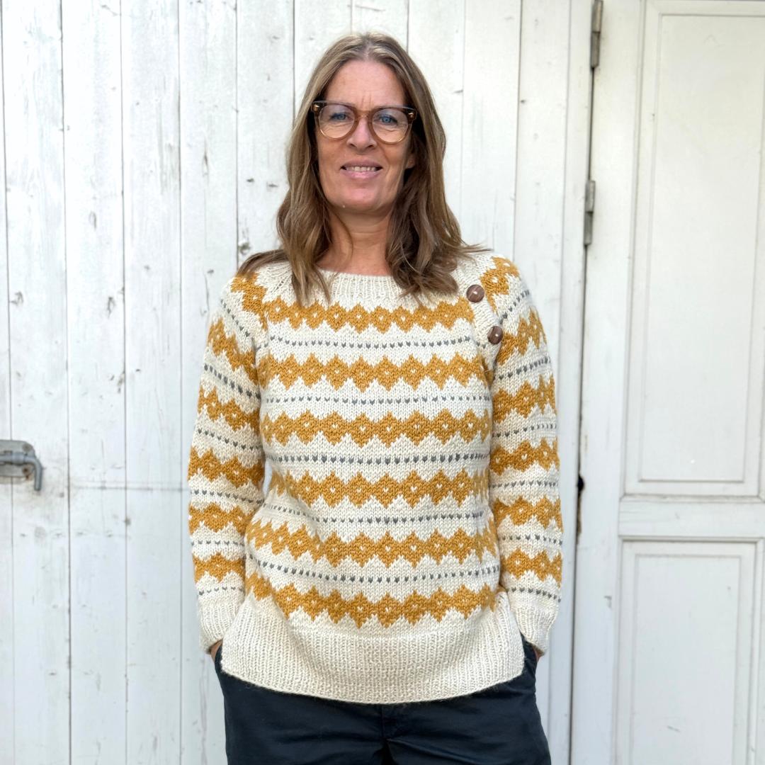 Hvid striktrøje fra Chola med gult strikket mønster. Trøjen er lavet af kvinder i Bolivia og er lavet i alpakauld