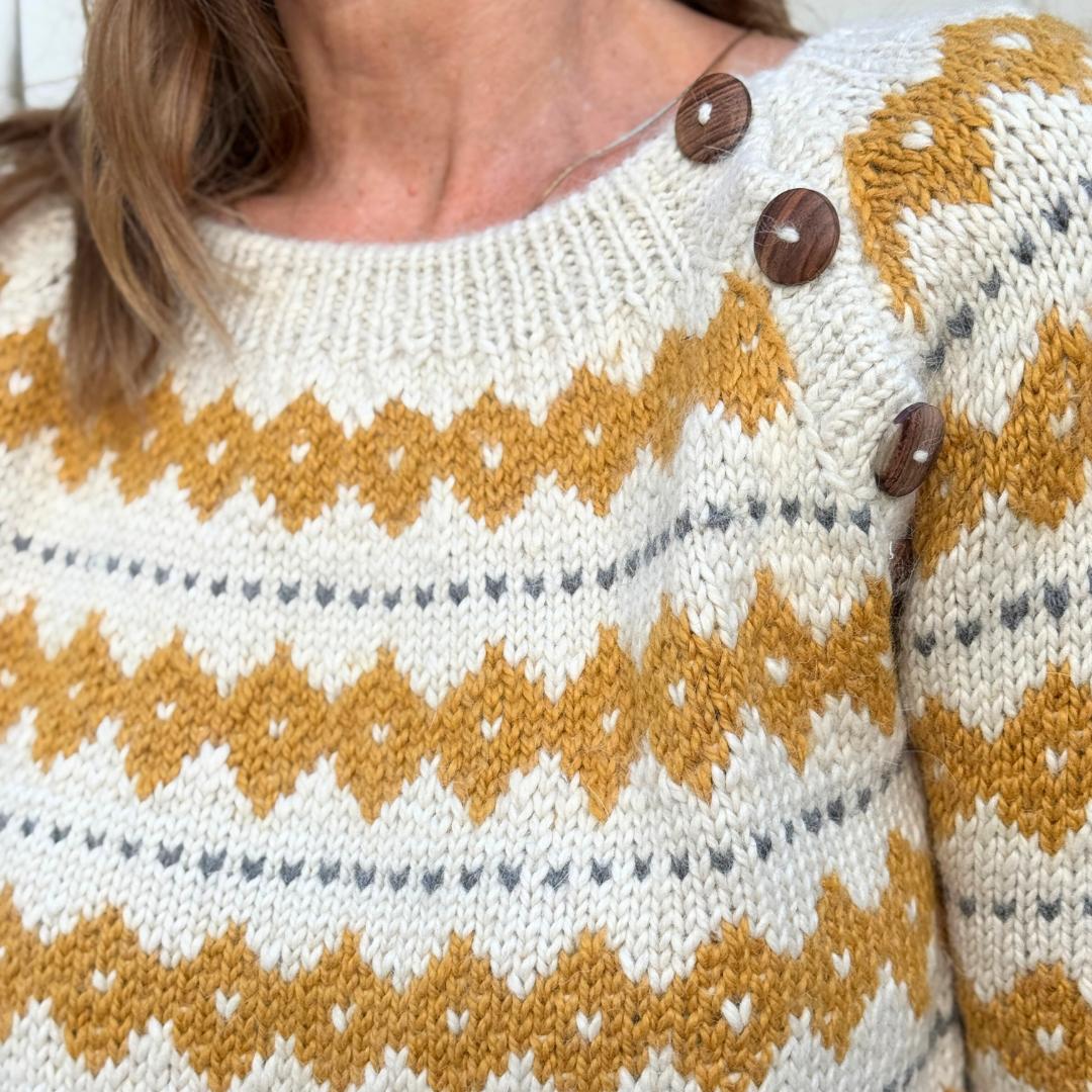 Hvid striktrøje fra Chola med gul strikket mønster. Trøjen er lavet af kvinder i Bolivia og er lavet i alpakauld