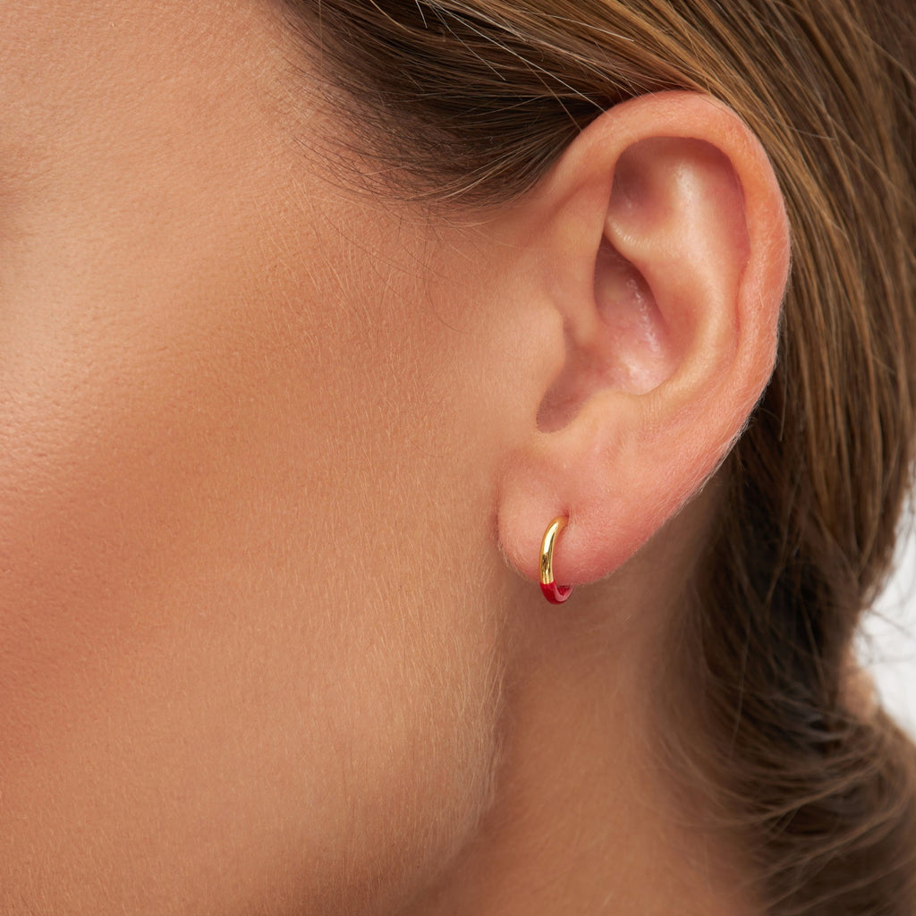 En lille hoop ørering fra Lulu Copenhagen som er guld, men halvdelen er dyppet i en rød farve