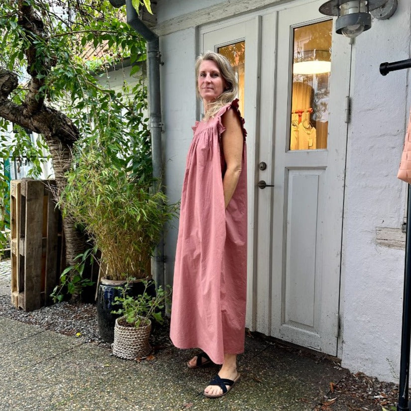 Stockholm kjolen fra FRAU er en lang kjole med flæser ved ærmerne. Den er vendbar og er i farven &