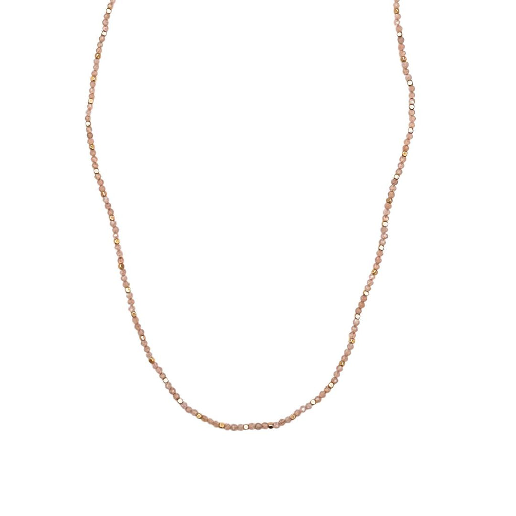 Stone Dot halskæden fra IBU Jewels er en tidløs halskæde. Modellen består af en farvet perle med en guldperle mellem hver anden til tredje farvet perle. 'Sunstone' er af en base af solsten. Stenene varierer i farve fra orange og svag lyserød