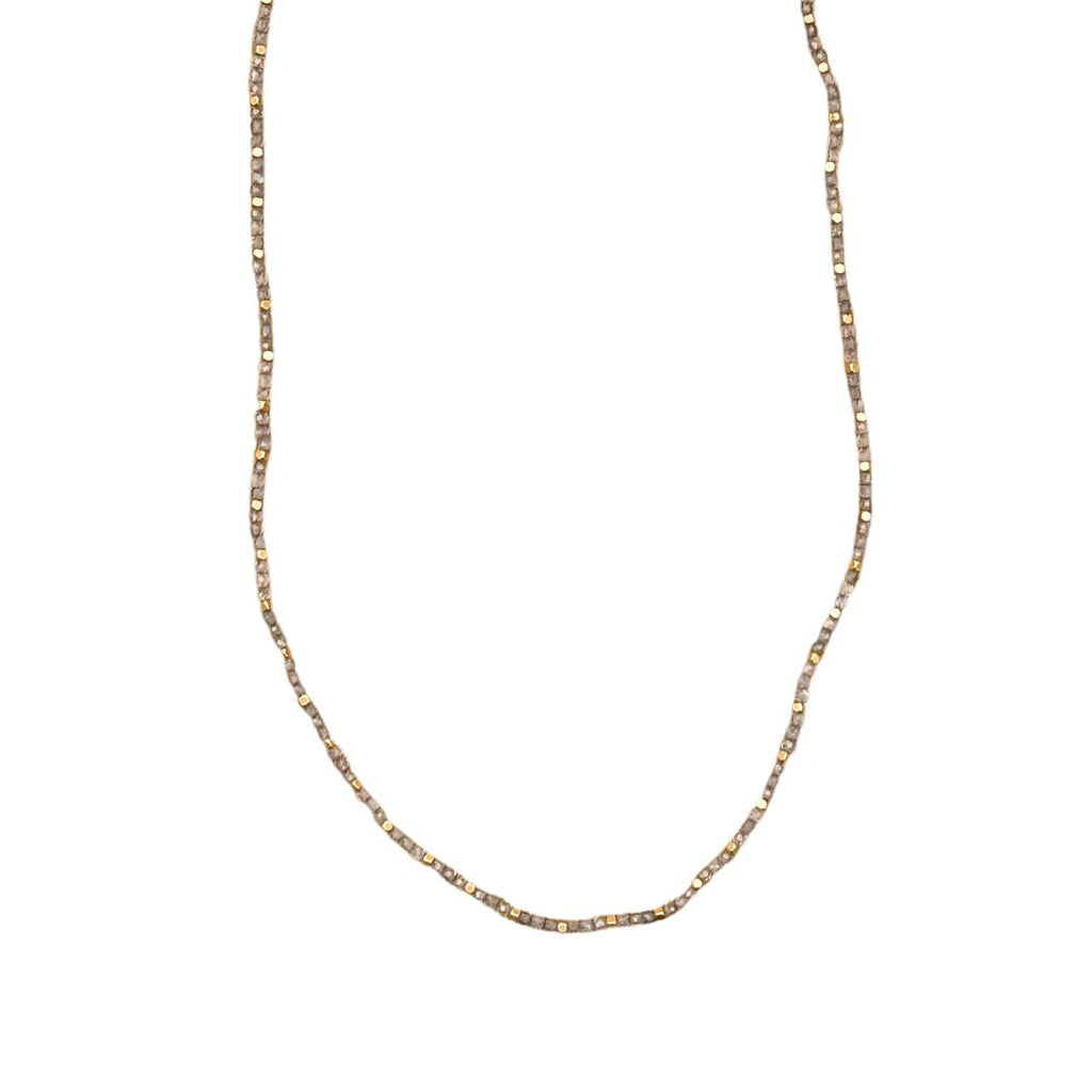Stone Dot halskæden fra IBU Jewels er en tidløs halskæde. Modellen består af en farvet perle med en guldperle mellem hver anden til tredje farvet perle. 'Labradorite' er af en base af labradorite sten. Stenene varierer i farven grå.