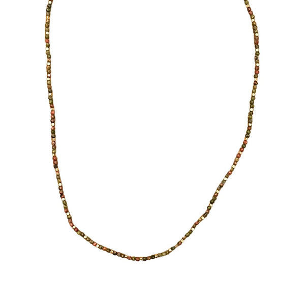 Stone Dot halskæden fra IBU Jewels er en tidløs halskæde. Modellen består af en farvet perle med en guldperle mellem hver anden til tredje farvet perle. 'Unakite' er af en base af Unakitesten. Unakite stenene varierer i farve fra plettet grå og pink.