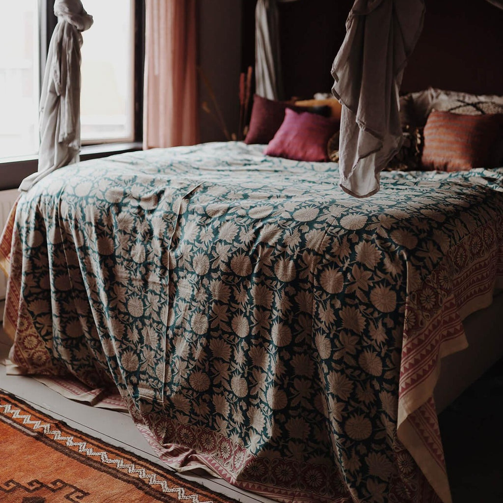 Et dug/sengetæppe med et blå blomstermønster i midten og en pink kant