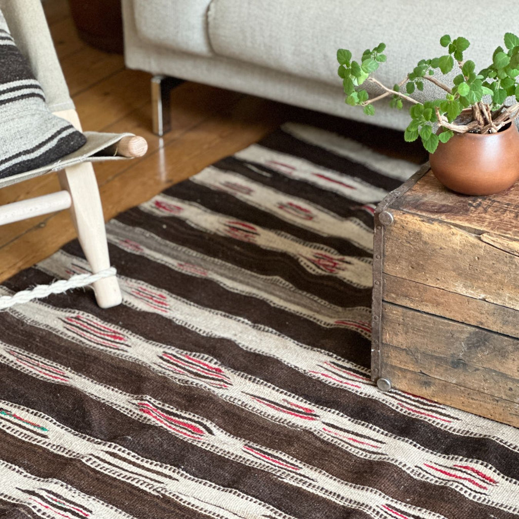 Et tyndere marokkansk unika gulvtæppe i brune, hvide og røde farver