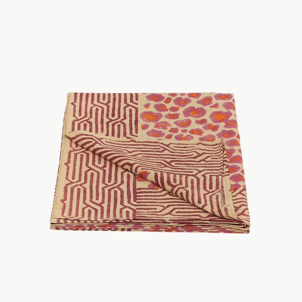 Et dug/sengetæppe med et pink og orange leopard mønster i midten og en rød mønstret kant