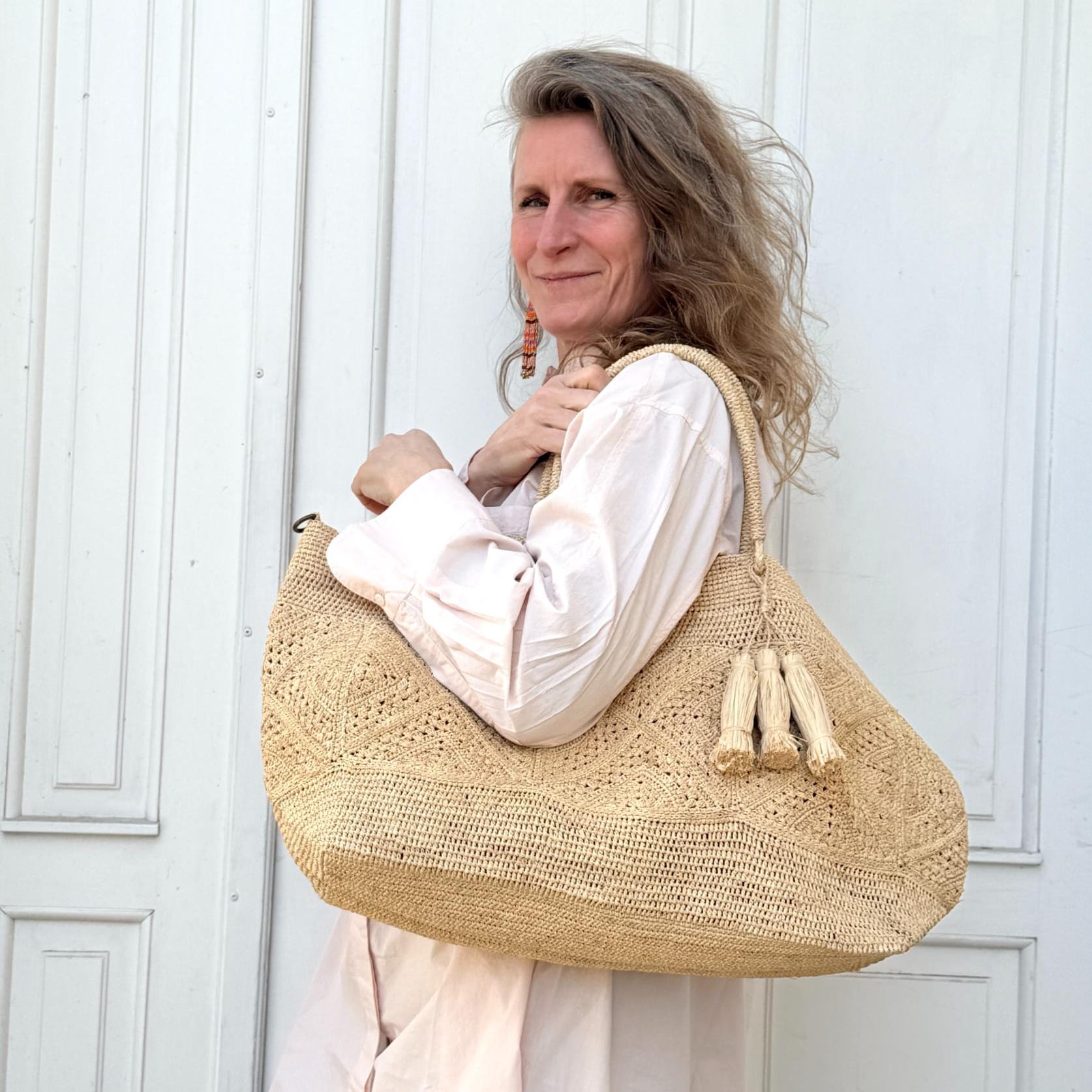 Lys flettet skuldertaske med kvaster og god plads til strand eller hverdag