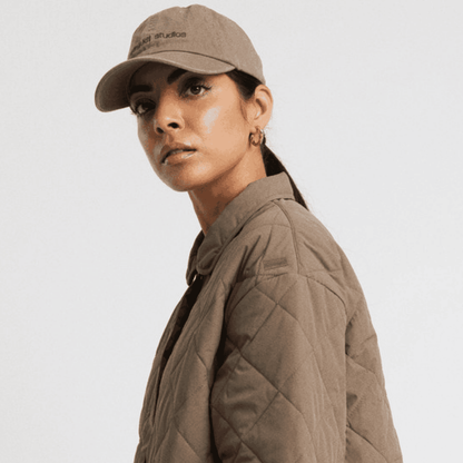 Brun baseball cap med brunt logo og justerbar rem med metalspænde.