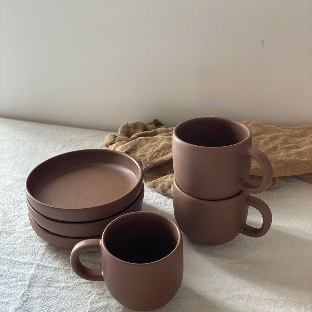 Den simple og minimalistiske Oktober kop er håndlaver af danske keramiker Julie Damhus. Kaffekoppen har en stor hank, der gør den behagelig at holde om - og så giver det kruset et smukt og råt design. Den har en dyb brun farve med en unik brunprikket glasur, der giver koppen et mat look