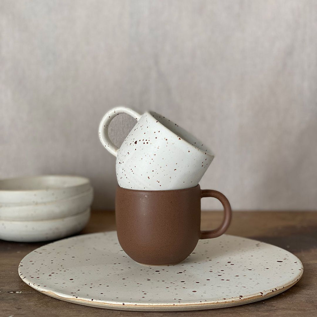 Den simple og minimalistiske Oktober kop er håndlaver af danske keramiker Julie Damhus. Kaffekoppen har en stor hank, der gør den behagelig at holde om - og så giver det kruset et smukt og råt design. Den har en flot hvid farve med en unik brunprikket glasur, der giver koppen et mat look.