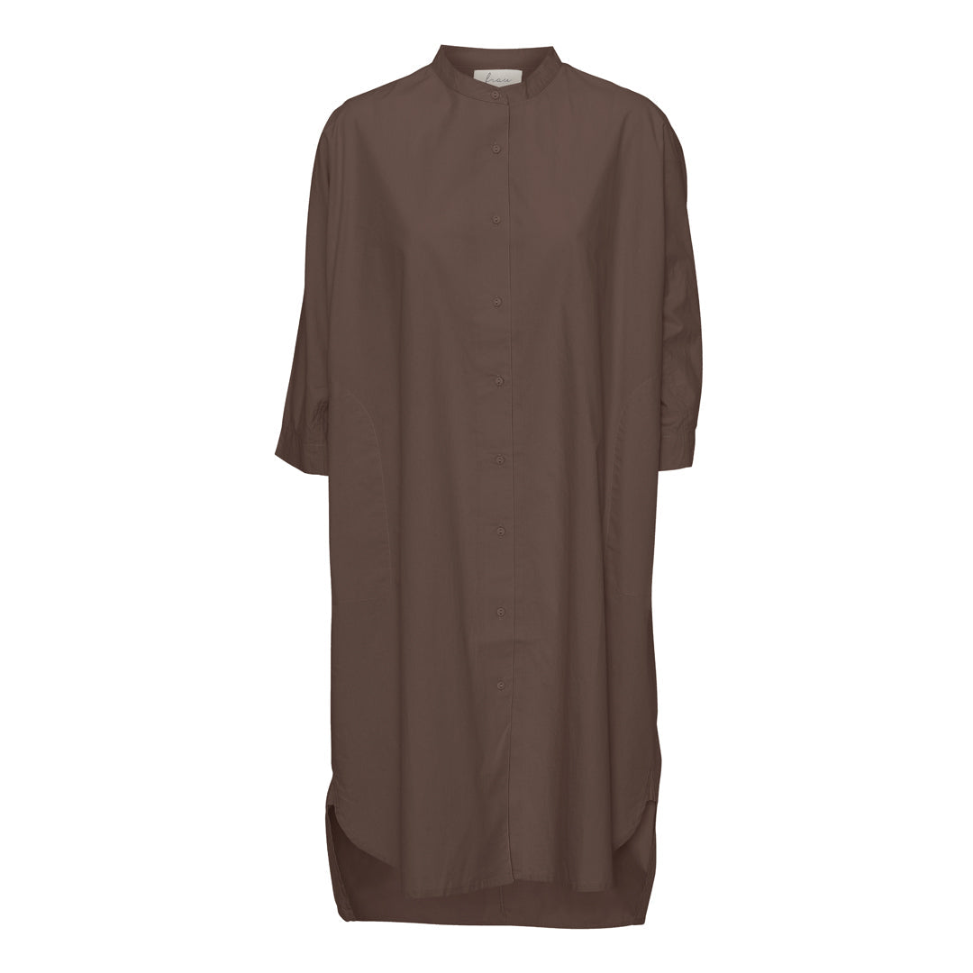 Brun oversized skjortekjole har 3/4 ærmer og en simpel kinakrave, der giver den et lækkert casual look. En anden skøn detalje er, at den har sidelommer. Modellen er one size og er lavet i 100% økologisk bomuld.