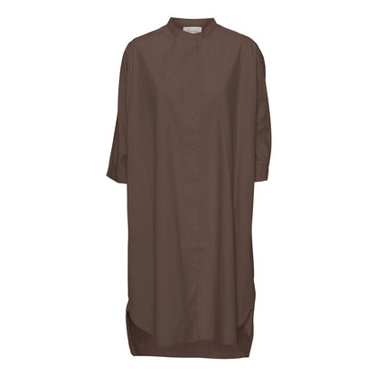 Brun oversized skjortekjole har 3/4 ærmer og en simpel kinakrave, der giver den et lækkert casual look. En anden skøn detalje er, at den har sidelommer. Modellen er one size og er lavet i 100% økologisk bomuld.