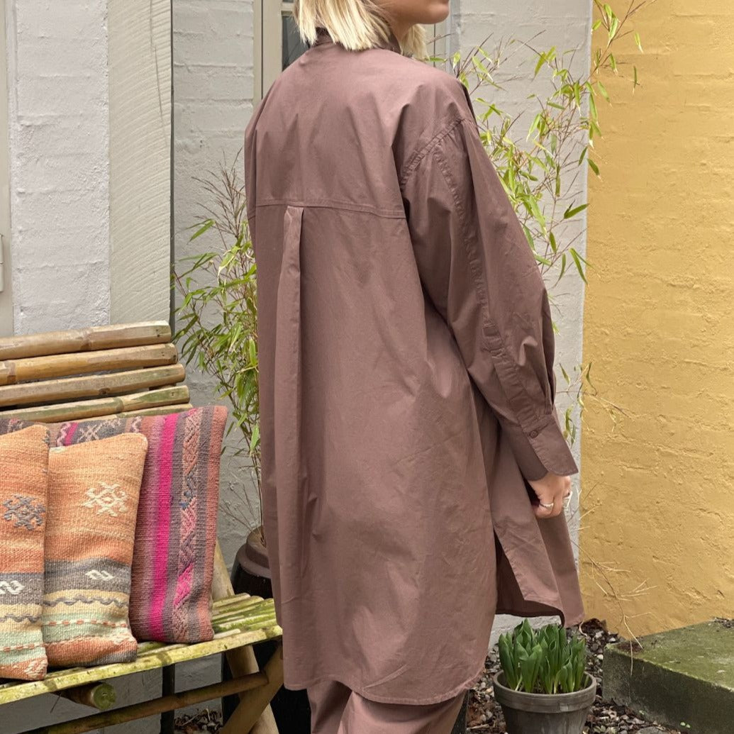 Den lange brune bomuldsskjorte i er en perfekt hverdagsskjorte fra Frau. Skjorten er lidt længere bagpå og runder fint foran. Skjorten er gennemknappet, og er lavet i økologisk bomuldspoplin, som gør den åndbar og behagelig at have på. Størrelsen er one size